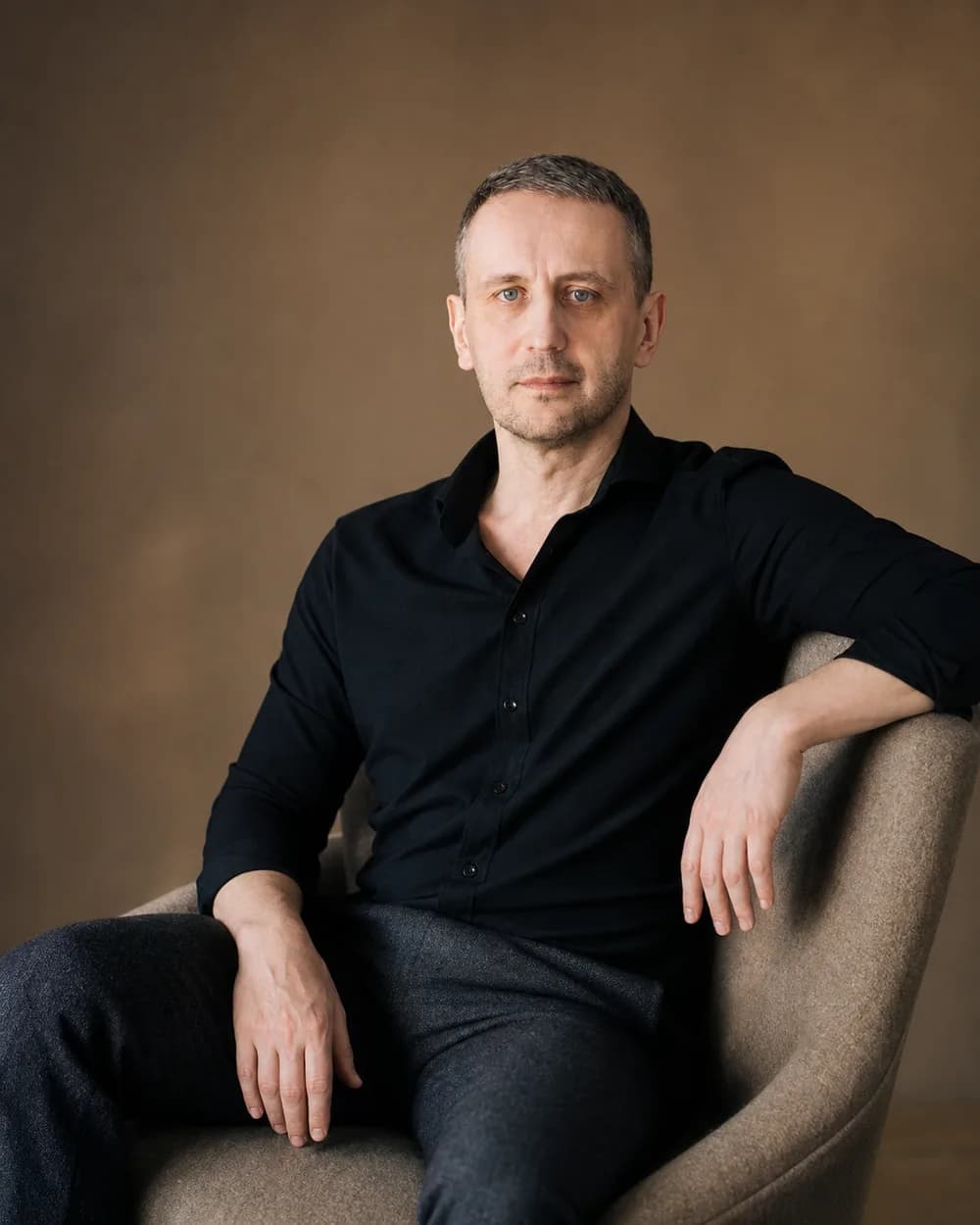 Александр Лосев сидит в кресле в спокойном тёплом интерьере